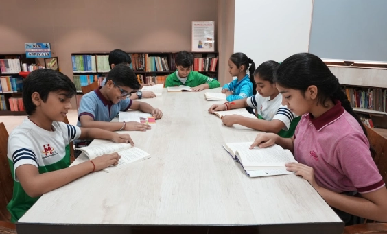 Middle schoolers reading quietly around a long table in a well‑stocked library, nurturing strong reading habits at MRIS Charmwood.